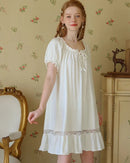 Woman drifting off in a white 100 % cotton nightdress, short flutter sleeves finished with delicate lace—airy, skin-friendly comfort for warm summer nights.