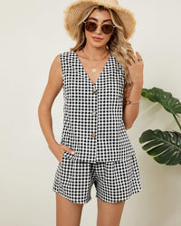 Model wearing gingham sleeveless V-neck top and matching shorts set, carrying woven handbag, casual summer style